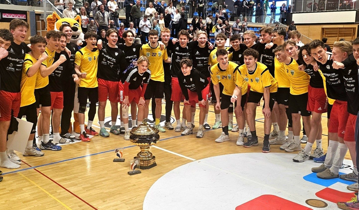 En rekke handballspillere med vinnerpokal i midten.